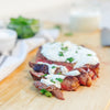 A sliced ribeye steak with blue cheese and chive sauce and herbs on a cutting board.