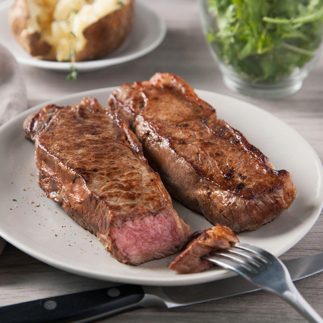 Two New York strips with a fork 