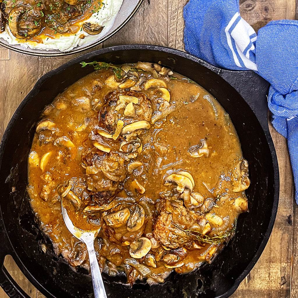 An overhead shot of a skillet of mashed potatoes and gravy and green beans with melted butter.