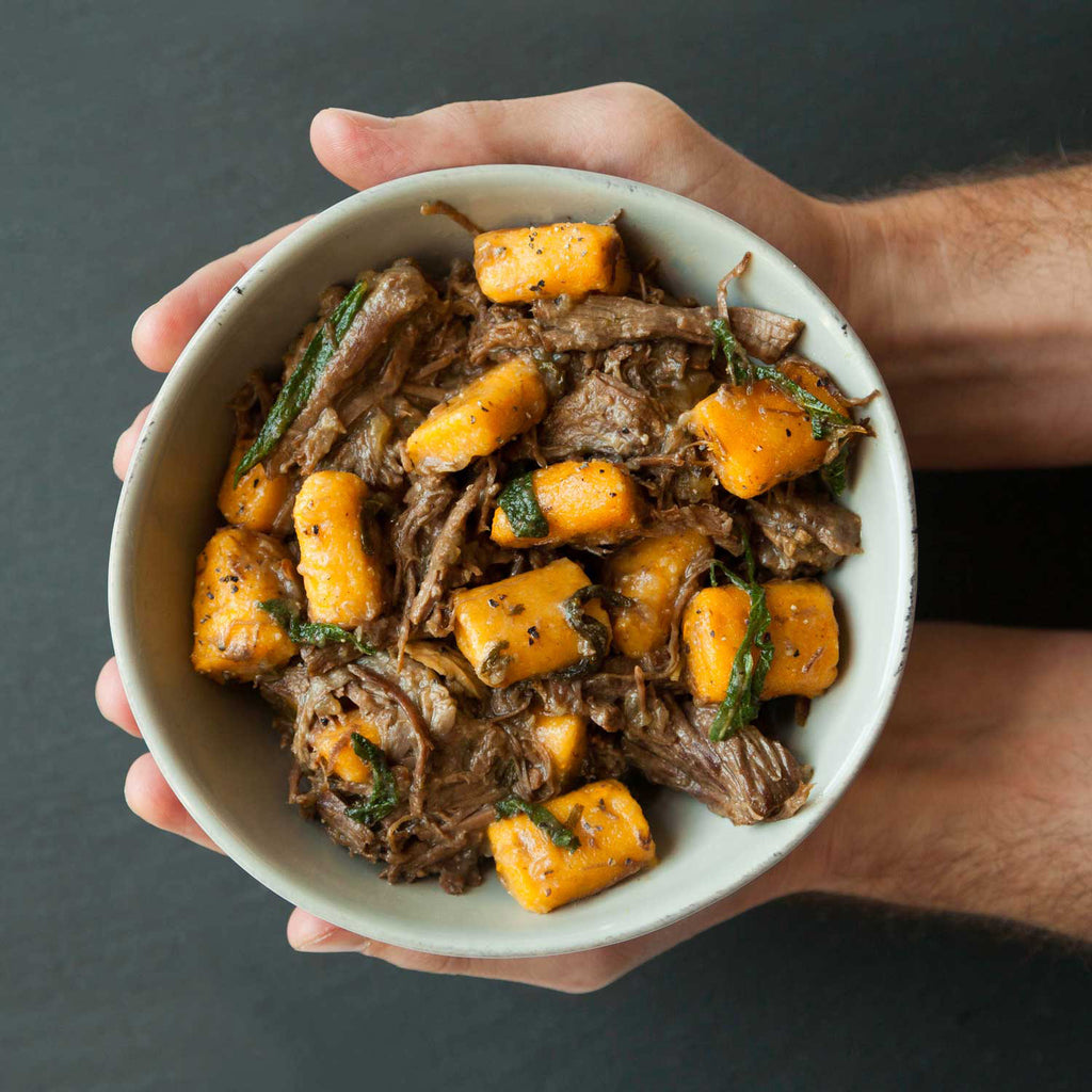 Sweet potato gnochi pillows and sage in a bowl with a person cupping it in their hands