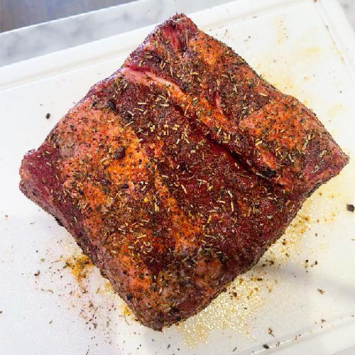The rib roast is sitting on the counter with spices on it.