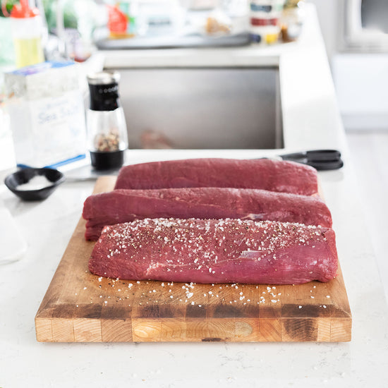 3 tenderloin roasts with seasoning on a cutting board 